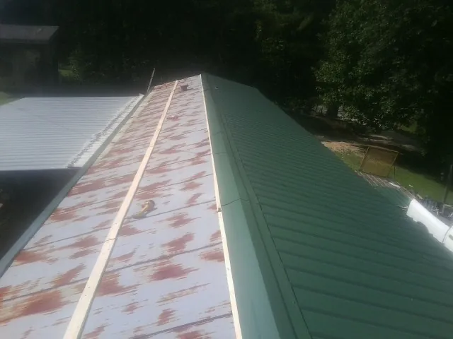 Old rusted panels beside newly installed green metal roofing — Wind Damage Roof Repair by Roofing Brothers in Cincinnati