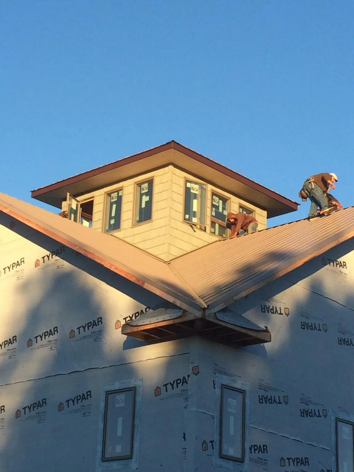 Roofers working around a rooftop cupola on a new metal roof at sunset — Roof Waterproofing in Cincinnati by Roofing Brothers
